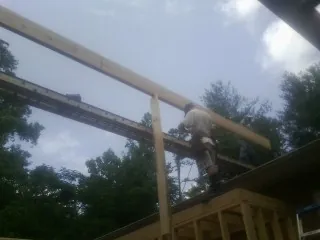 Carpenter setting a ridge beam over a new addition frame — Ice Dam Removal by Roofing Brothers in Fraser