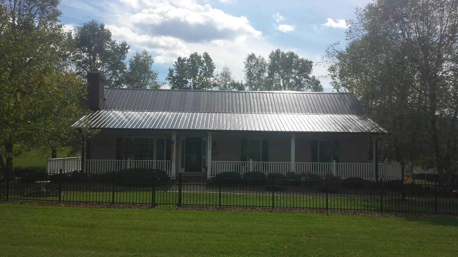 Gray metal roof on a brick ranch with a full width front porch — Gutter Guard Installation work by our crew in Fraser