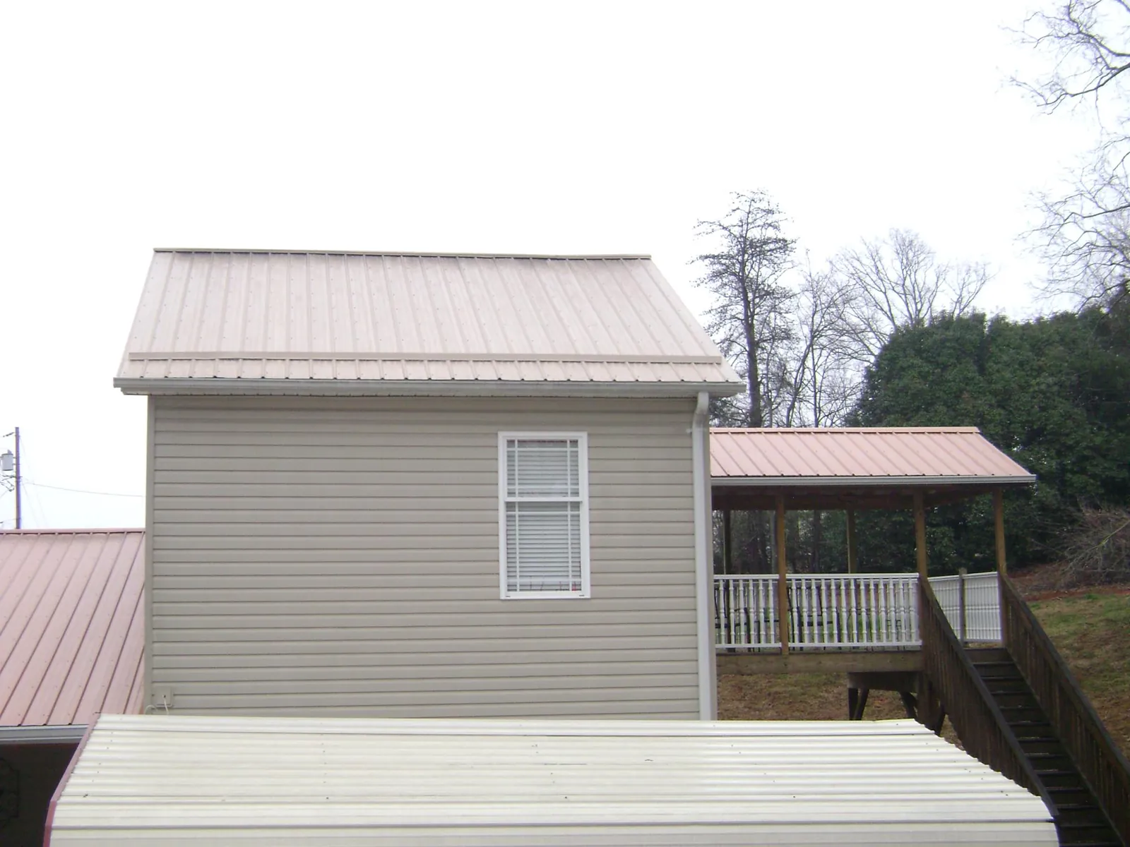 Tan metal roofs on a two story addition and attached porch, from a Roof Replacement job in Fraser