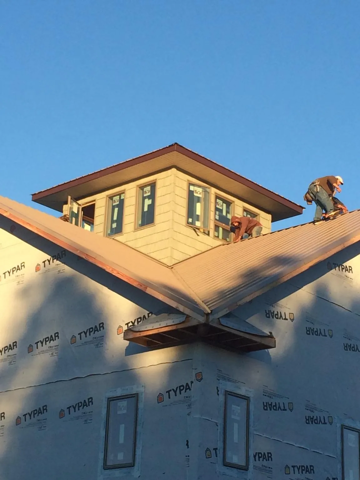 Roofers working around a rooftop cupola on a new metal roof at sunset — Roof Waterproofing in Fraser by Roofing Brothers